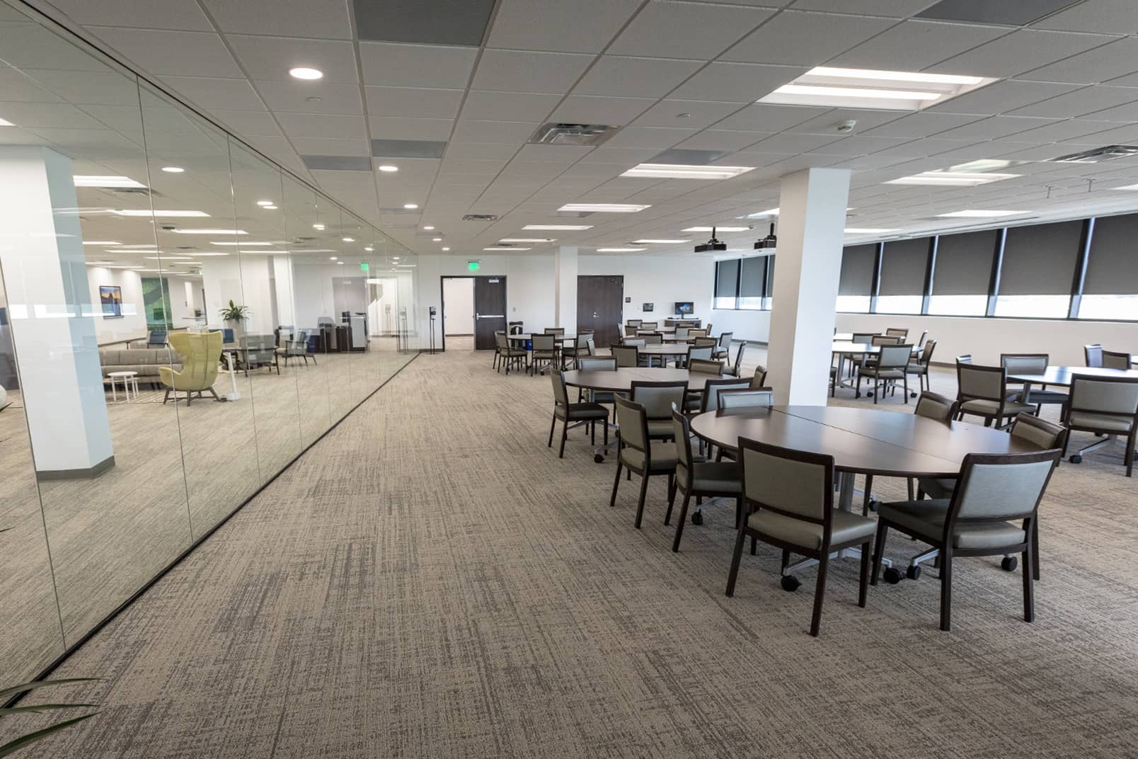 Large open training space with round tables and chairs, separated by glass walls, designed for collaborative learning and meetings.