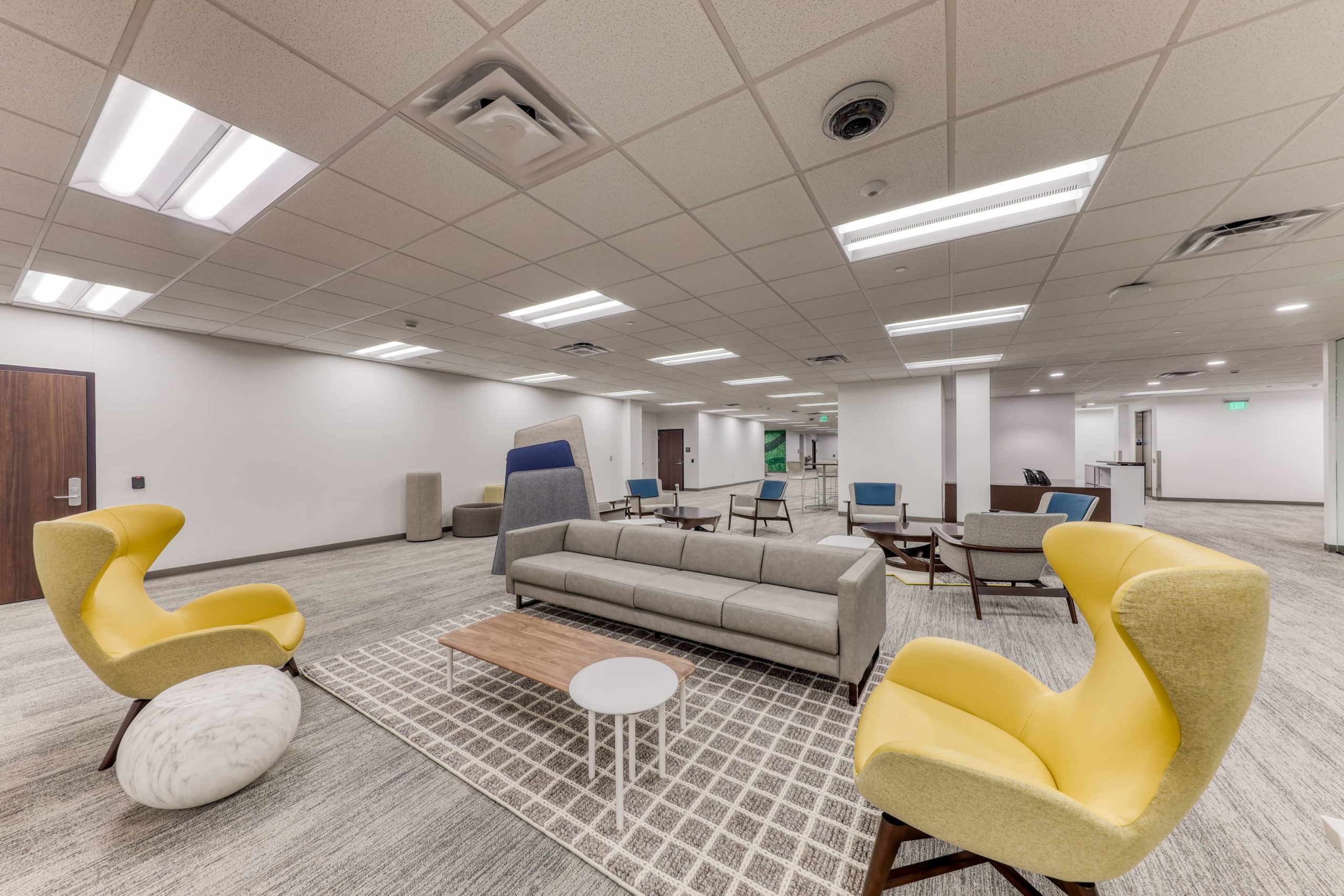 Open lounge and collaboration area with sofas, lounge chairs, low tables, and flexible seating arrangements.