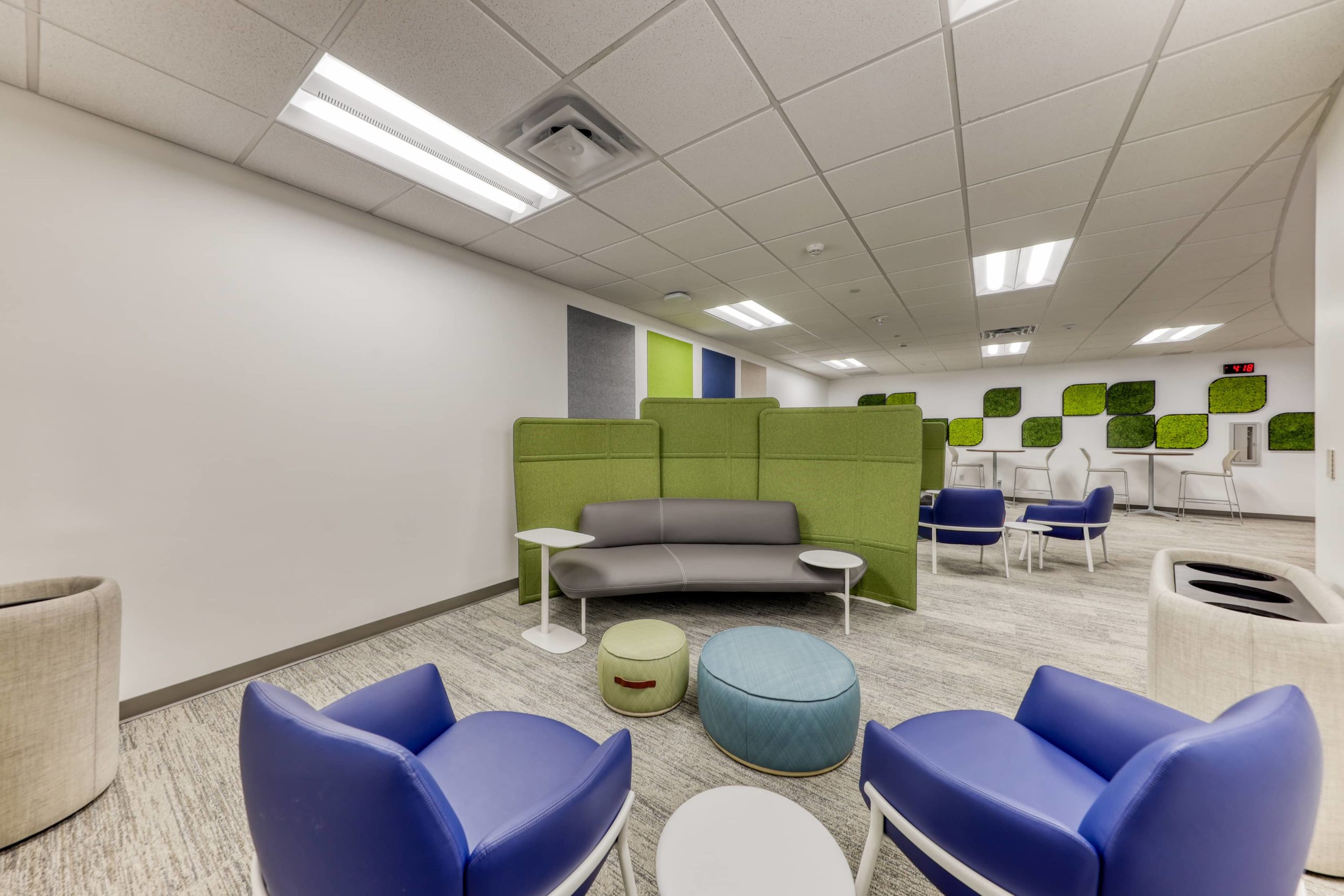 Informal breakout area with curved seating, acoustic privacy panels, stools, and soft seating for group discussion.