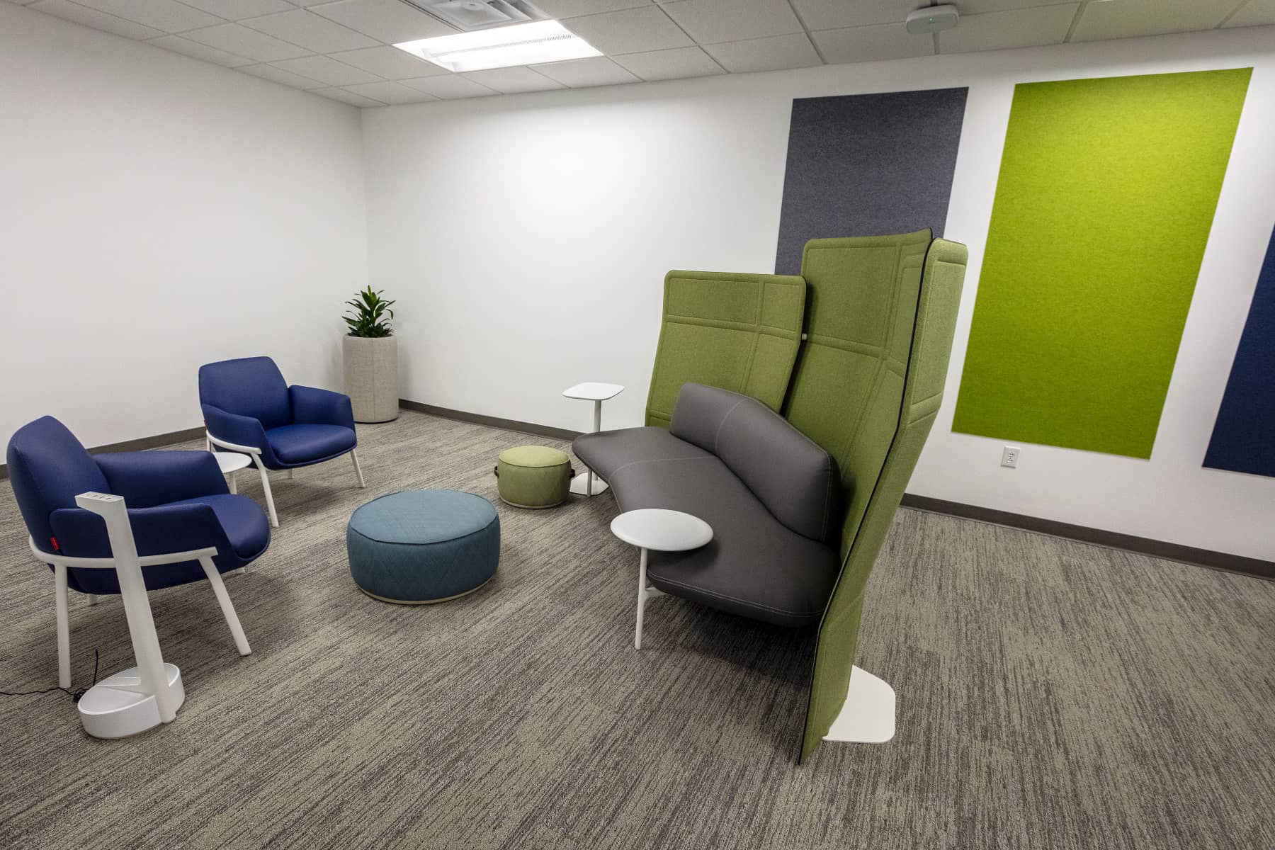 Small collaborative seating area with high-backed lounge furniture, side tables, and acoustic wall panels for focused conversation.